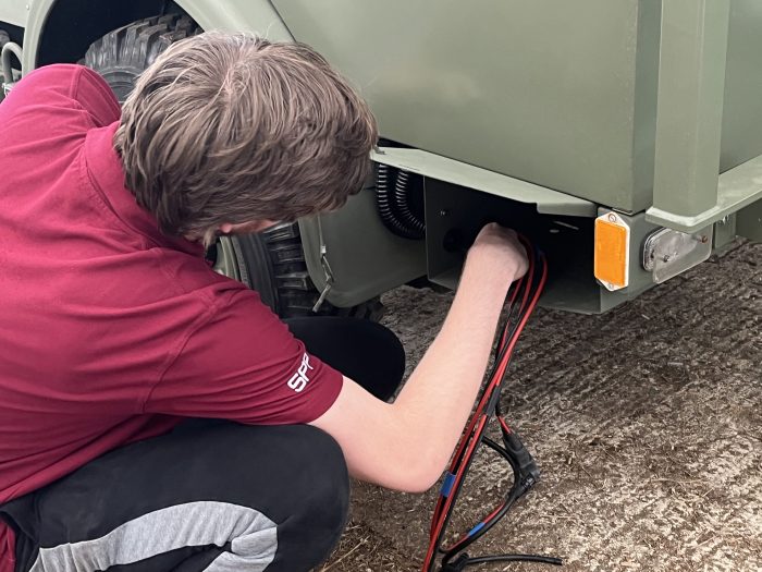 Male student placement working on the electronics of a vehicle